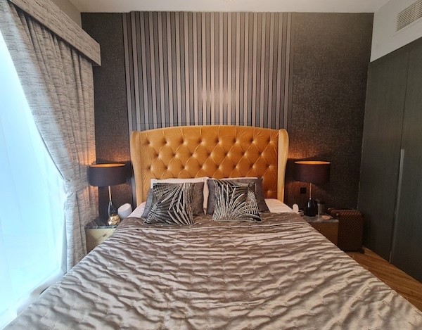 AG tower bedroom with weir niche, home styling in dubaiu, dubai home styling and decor, boutique hotel style dark bedroom with mustard bed, wall paneling, black wallpaper glam