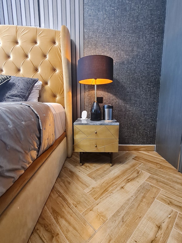 AG tower bedroom with weird niche, home styling in dubai, dubai home styling and decor, boutique hotel style dark bedroom with mustard bed, wall paneling, herringbone tiles