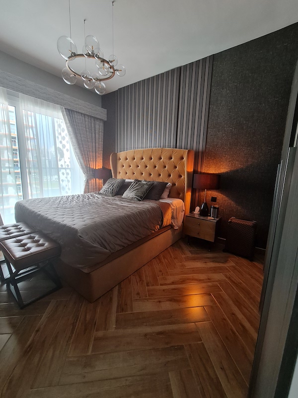AG tower bedroom with weird niche, home styling in dubai, dubai home styling and decor, boutique hotel style dark bedroom with mustard bed, wall paneling, herringbone tiles